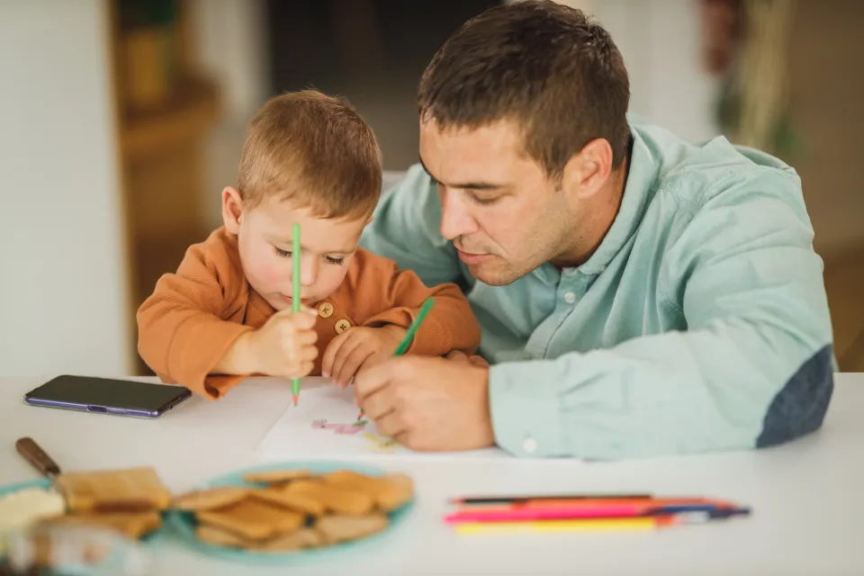 An adult helping a child with a drawing activity