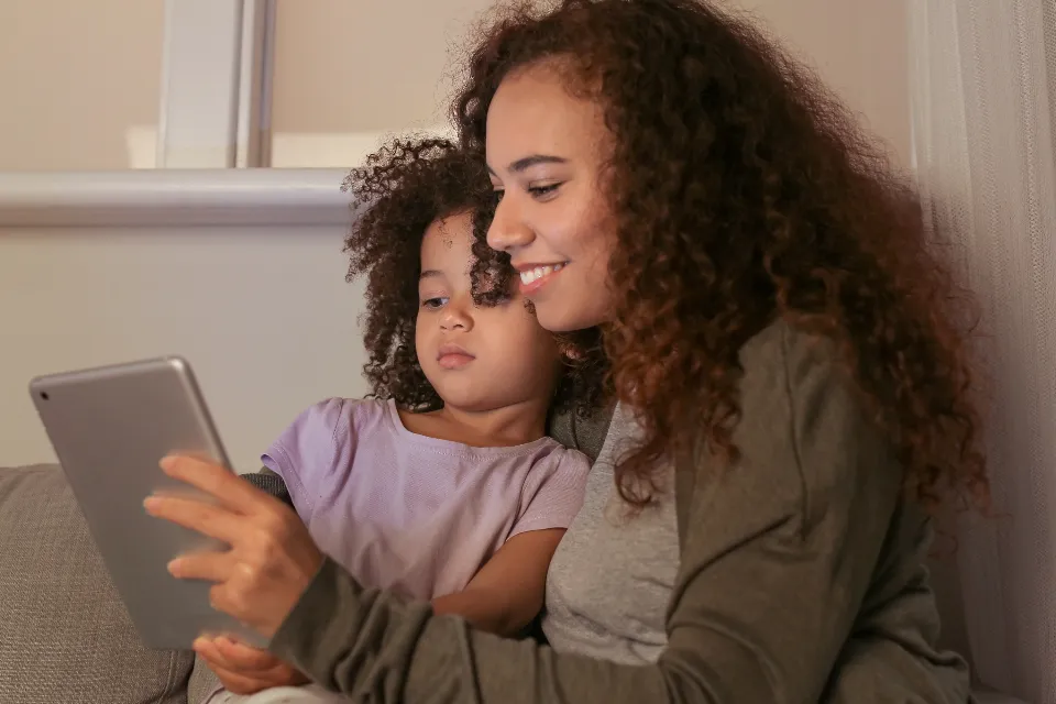 A parent and child looking at a tablet together
